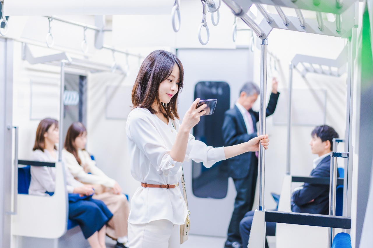 Woman watching YouTube content from Japanese vloggers on train in 2023